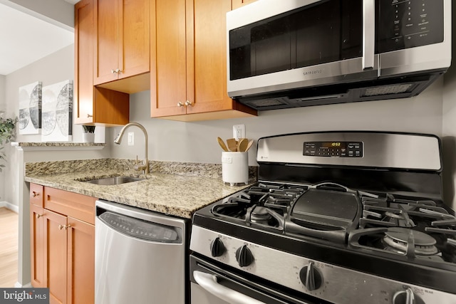 kitchen featuring light stone countertops, appliances with stainless steel finishes, and sink