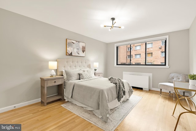 bedroom with light hardwood / wood-style floors and a chandelier