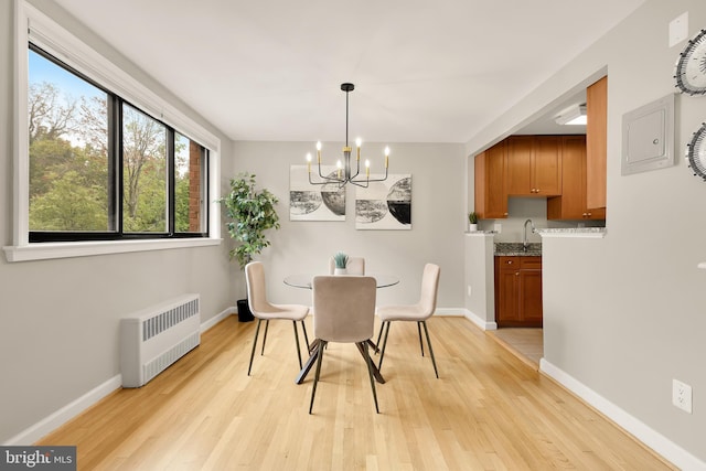 dining space featuring light hardwood / wood-style floors, an inviting chandelier, radiator, and sink