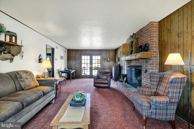 carpeted living room featuring a fireplace, wooden walls, and french doors