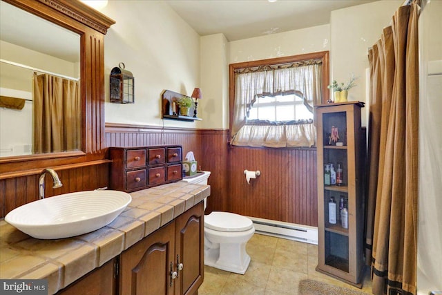 bathroom featuring vanity, a baseboard radiator, toilet, and wood walls