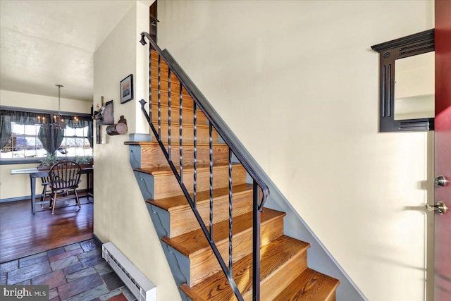 stairs with a chandelier and a baseboard heating unit