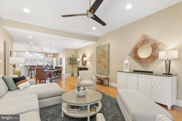 living room with light hardwood / wood-style flooring and ceiling fan