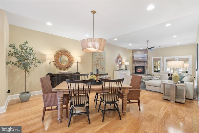 dining area featuring ceiling fan, a fireplace, and light hardwood / wood-style floors