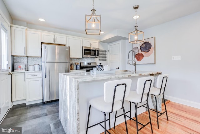 kitchen featuring white cabinetry, stainless steel appliances, decorative light fixtures, and decorative backsplash