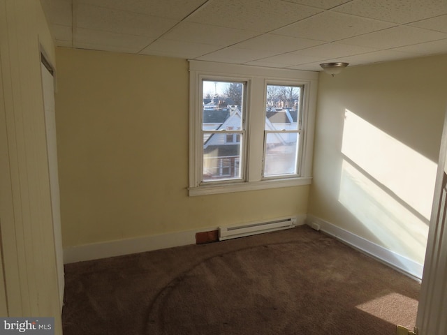 empty room with carpet floors, a drop ceiling, and baseboard heating