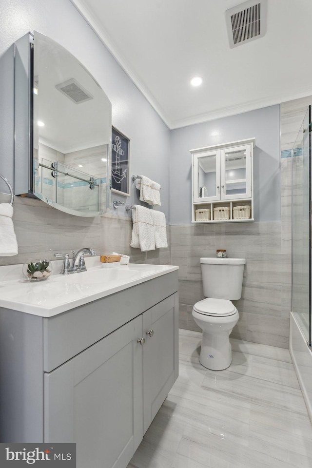 bathroom featuring vanity, tile walls, and toilet