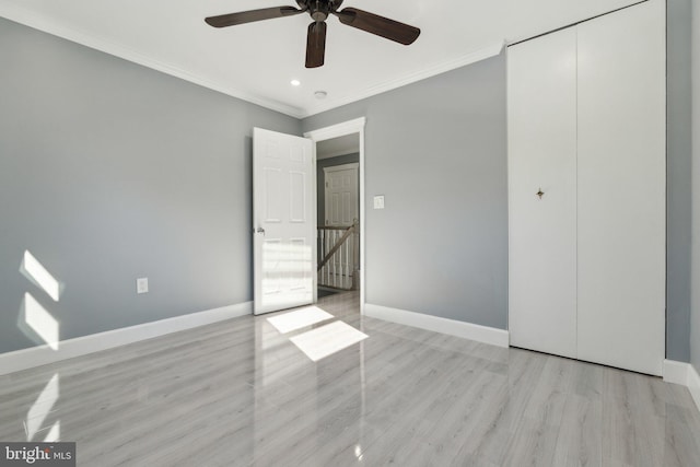 unfurnished bedroom featuring ceiling fan, light hardwood / wood-style floors, crown molding, and a closet