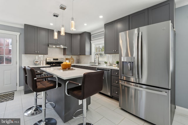 kitchen featuring stainless steel appliances, sink, light tile patterned floors, a center island, and hanging light fixtures