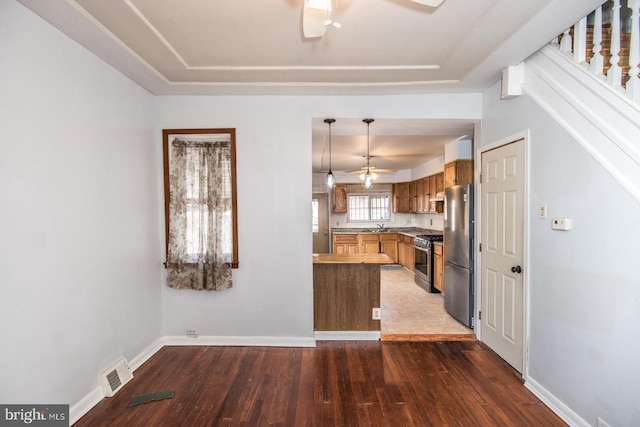 kitchen featuring ceiling fan, hanging light fixtures, stainless steel appliances, dark hardwood / wood-style flooring, and kitchen peninsula