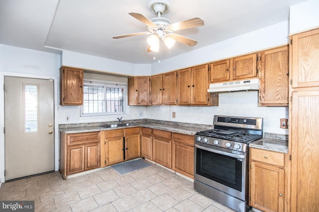 kitchen with gas stove, light stone counters, ceiling fan, and sink