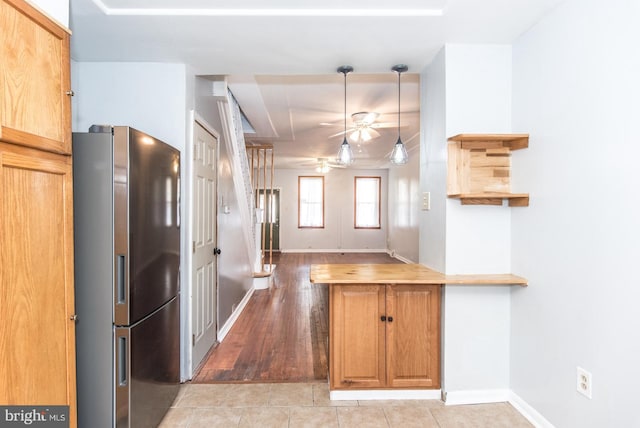 kitchen with stainless steel refrigerator with ice dispenser, hanging light fixtures, ceiling fan, butcher block countertops, and light tile patterned flooring