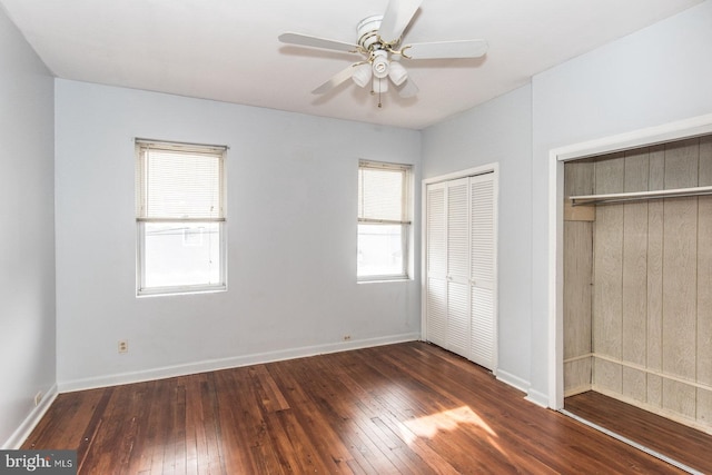 unfurnished bedroom with multiple windows, ceiling fan, and dark hardwood / wood-style floors