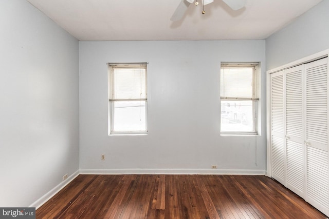 unfurnished bedroom with multiple windows, ceiling fan, a closet, and dark wood-type flooring