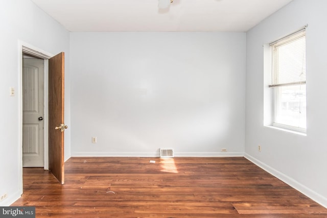 empty room with dark hardwood / wood-style flooring and plenty of natural light