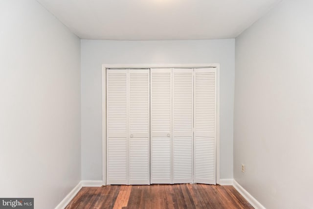 unfurnished bedroom featuring dark hardwood / wood-style flooring and a closet