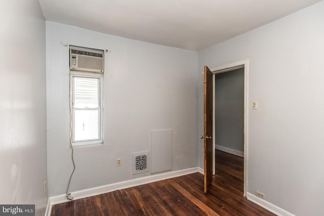 empty room featuring a wall mounted air conditioner and dark hardwood / wood-style floors