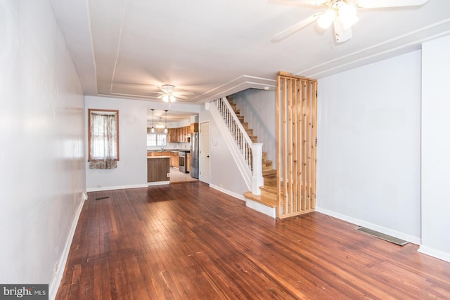 unfurnished living room featuring ceiling fan and dark wood-type flooring