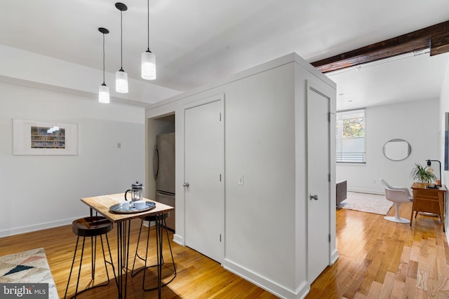 dining area featuring beam ceiling and light hardwood / wood-style flooring