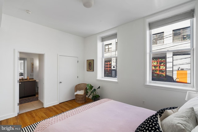 bedroom featuring ensuite bathroom and light hardwood / wood-style flooring