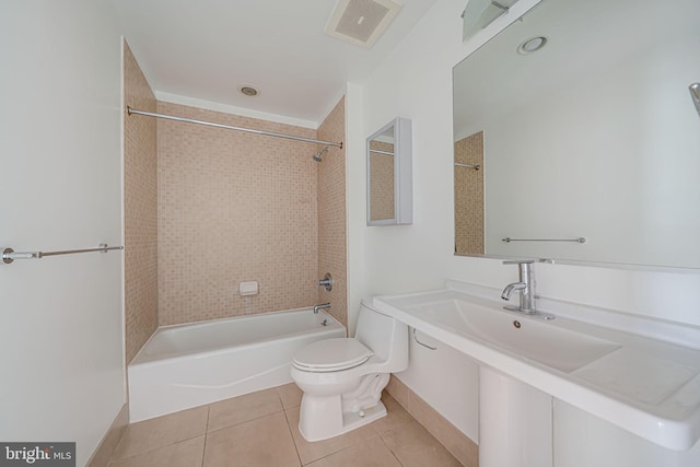 bathroom with tile patterned floors, tiled shower / bath combo, and toilet