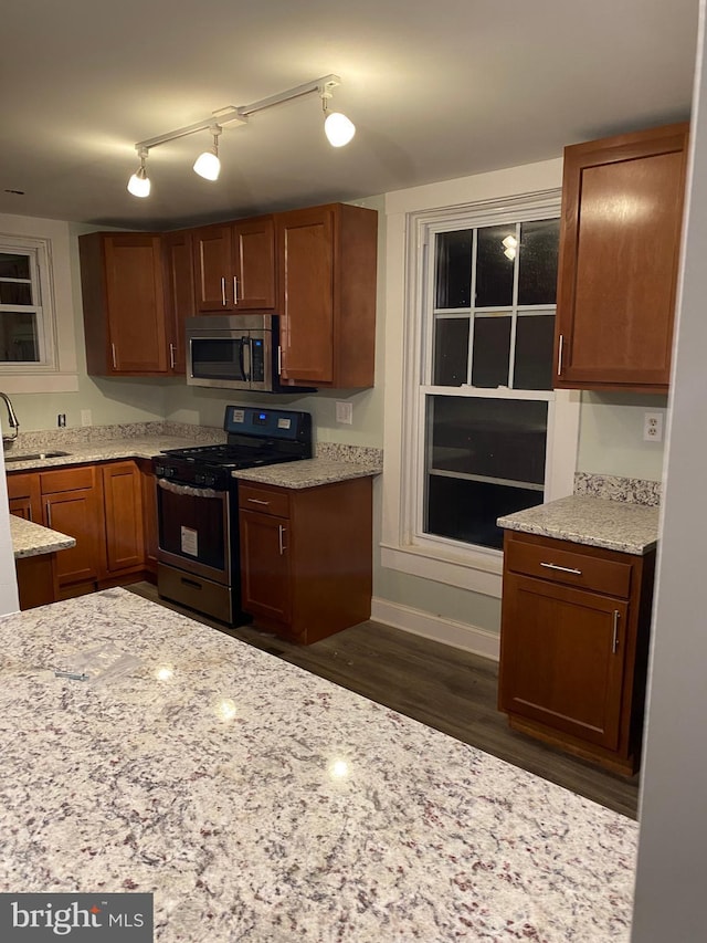 kitchen featuring light stone countertops, sink, appliances with stainless steel finishes, and dark wood-type flooring