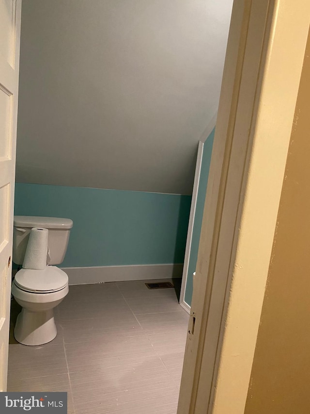 bathroom featuring tile patterned floors, lofted ceiling, and toilet