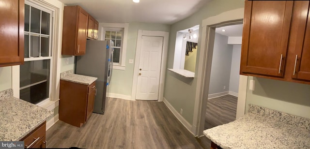 kitchen with dark hardwood / wood-style floors, light stone counters, and stainless steel refrigerator