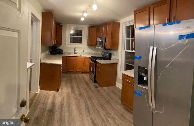 kitchen featuring light stone counters, sink, wood-type flooring, and stainless steel appliances