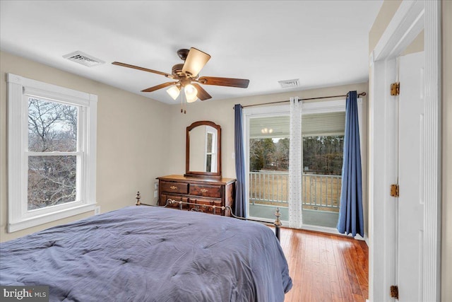 bedroom featuring access to outside, multiple windows, ceiling fan, and wood-type flooring