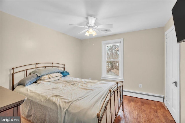 bedroom featuring hardwood / wood-style floors, ceiling fan, and baseboard heating