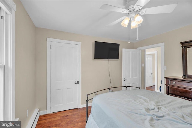 bedroom featuring baseboard heating, a closet, ceiling fan, and hardwood / wood-style floors