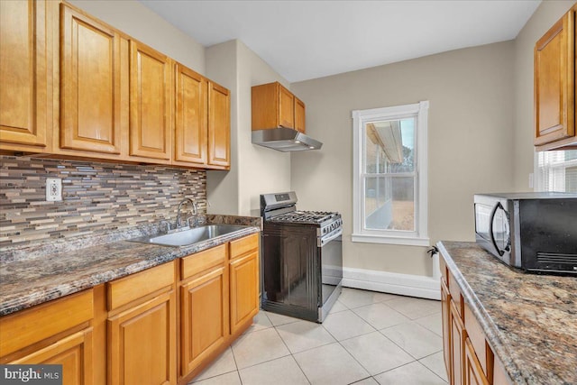 kitchen featuring sink, tasteful backsplash, dark stone counters, light tile patterned floors, and appliances with stainless steel finishes