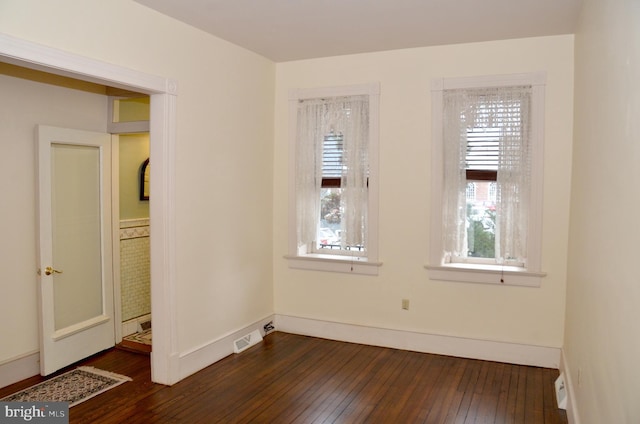 spare room with dark wood-type flooring and plenty of natural light