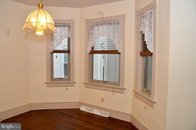 empty room with an inviting chandelier and hardwood / wood-style flooring