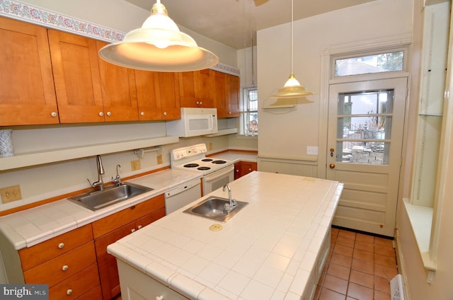 kitchen featuring sink, white appliances, tile countertops, and an island with sink