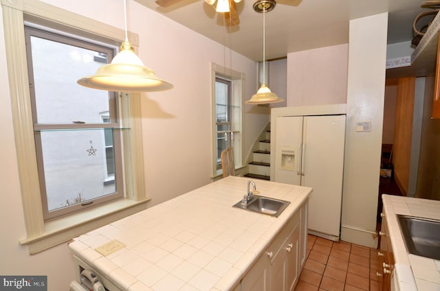 kitchen with sink, a center island with sink, tile counters, and white fridge with ice dispenser