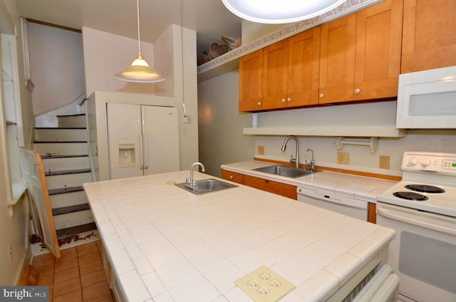 kitchen featuring white appliances, hanging light fixtures, tile countertops, and sink