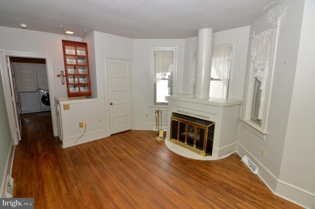 unfurnished living room with separate washer and dryer, a healthy amount of sunlight, and dark hardwood / wood-style floors