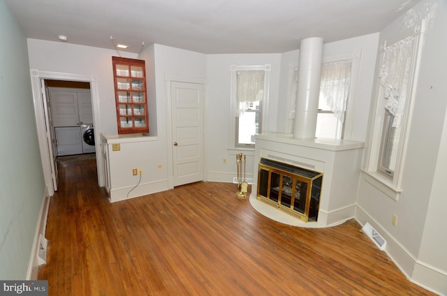 unfurnished living room with dark hardwood / wood-style flooring and separate washer and dryer