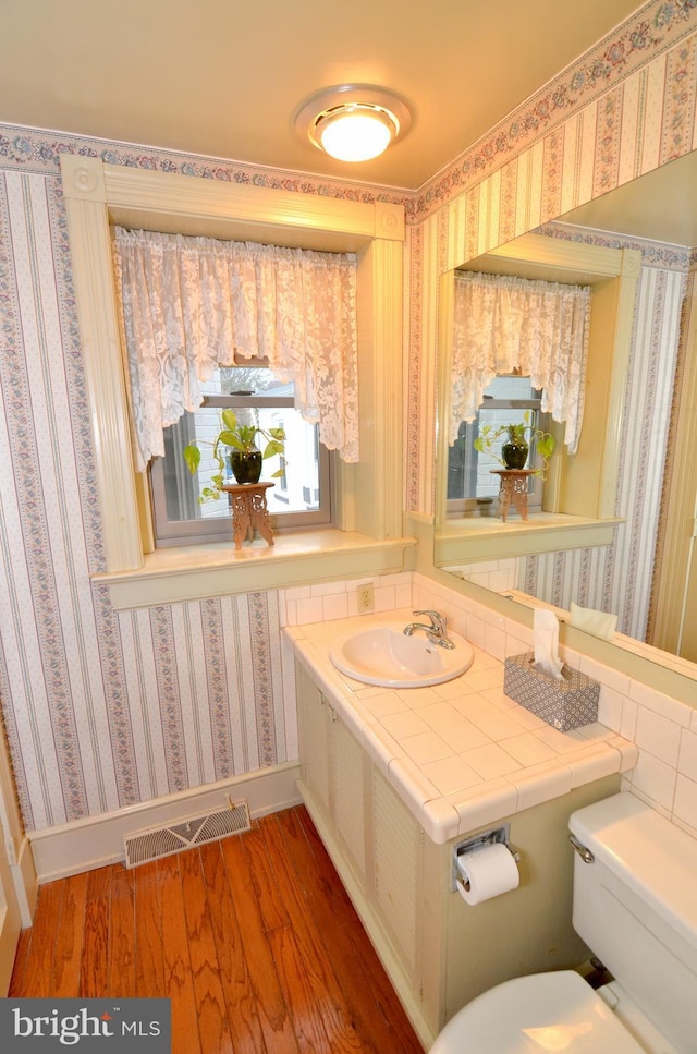 bathroom with toilet, wood-type flooring, and sink