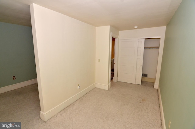 unfurnished bedroom featuring light colored carpet and a closet