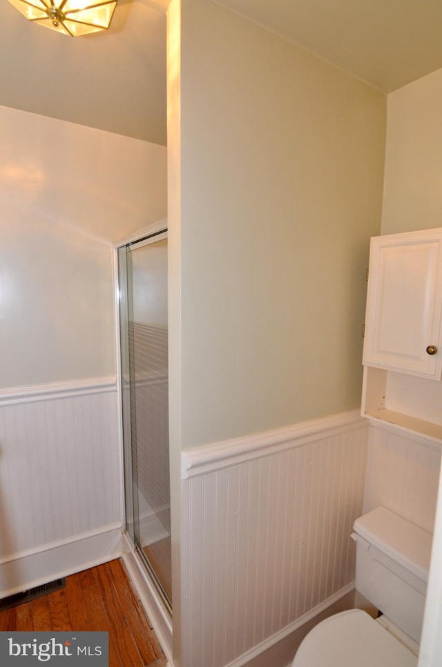 bathroom featuring toilet, hardwood / wood-style flooring, and an enclosed shower