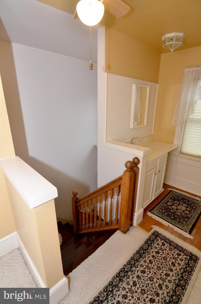 stairway featuring wood-type flooring and ceiling fan