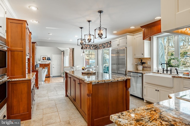 kitchen featuring white cabinetry, sink, a kitchen island, decorative light fixtures, and stainless steel appliances