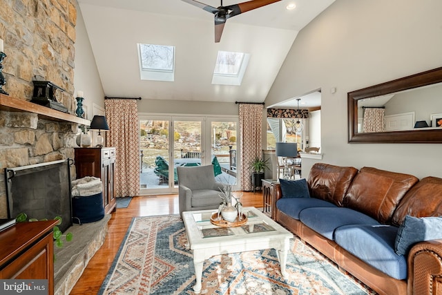 living room with light hardwood / wood-style floors, vaulted ceiling with skylight, and a fireplace