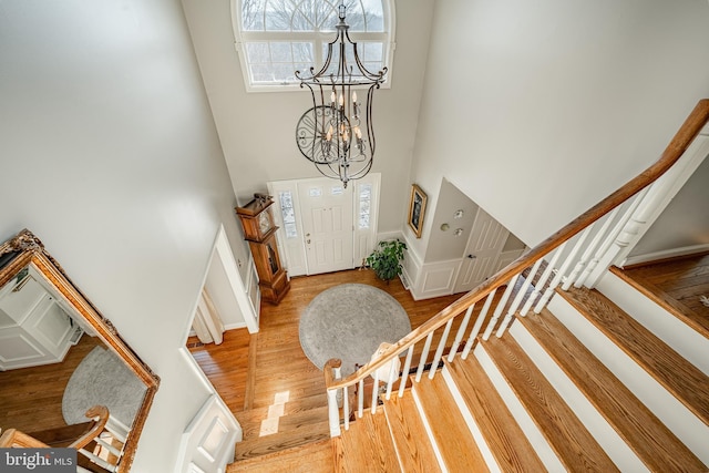 foyer with light hardwood / wood-style floors, a chandelier, and a high ceiling