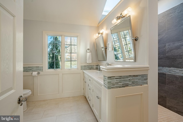 bathroom with toilet, tile patterned flooring, vaulted ceiling, and vanity