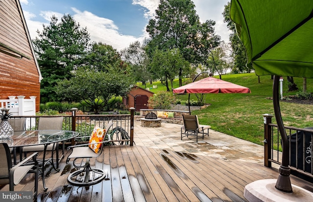 wooden terrace with an outdoor fire pit and a yard