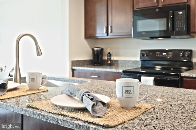 kitchen featuring dark brown cabinetry, light stone countertops, black appliances, and sink